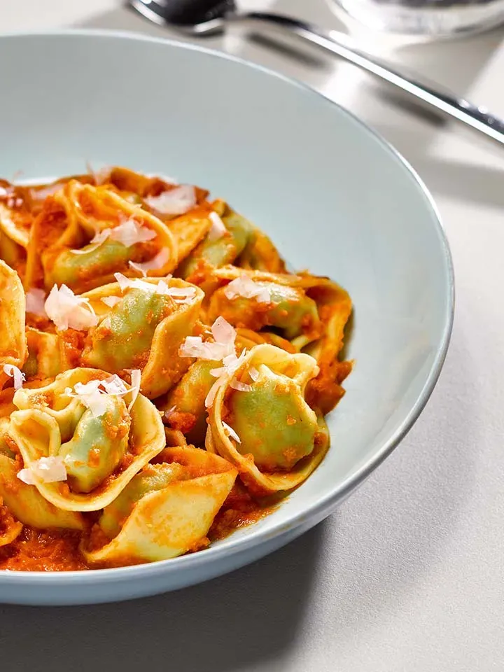 Tortelloni mit Tomatensauce und verstecktem Gemüse, Kindergericht mit Parmesan auf einem Teller