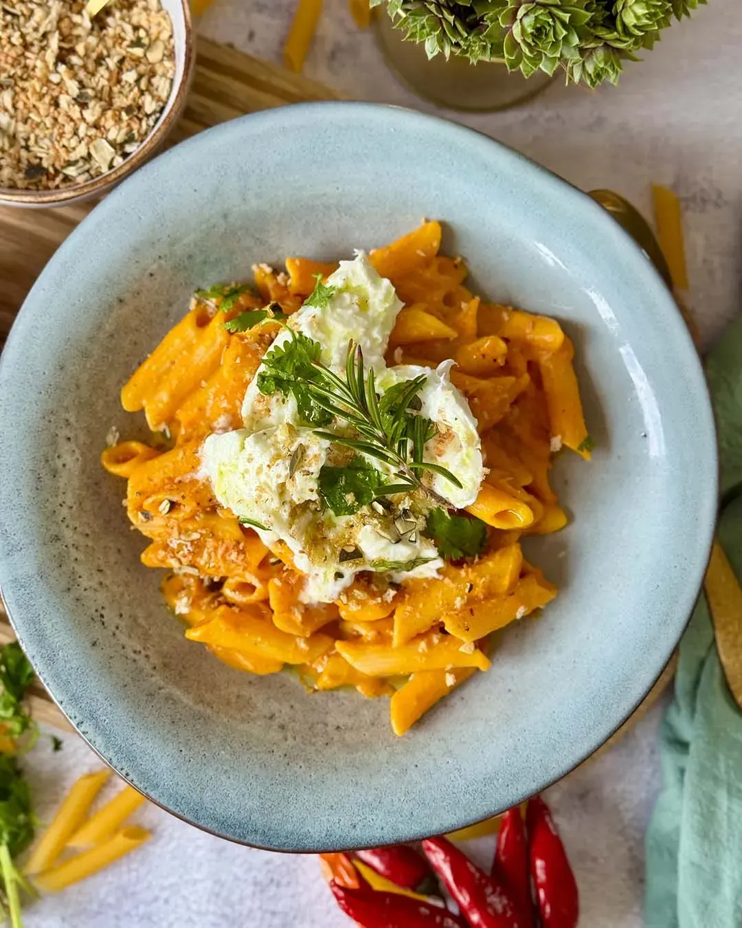 Aufsicht auf einen Teller Kürbis-Feta-Pasta mit Burrata, Kräutern und geröstetem Topping