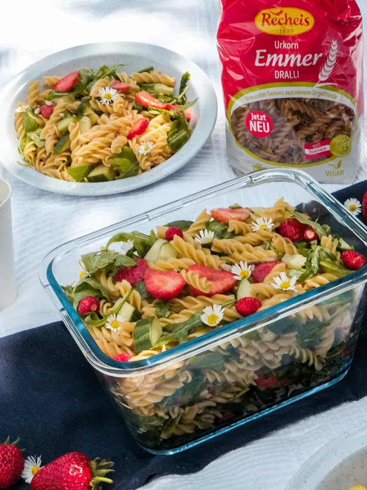 Urkorn-Nudelsalat mit Erdbeeren und Blüten in Glasbehälter und auf Teller mit Emmer-Nudeln