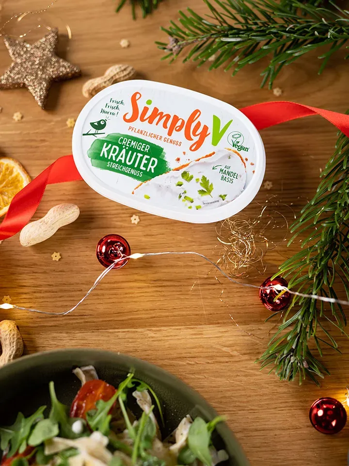 Pflanzlicher Kräuteraufstrich für vegane Frischkäsenudeln auf Holz mit Weihnachtsdeko und Salat