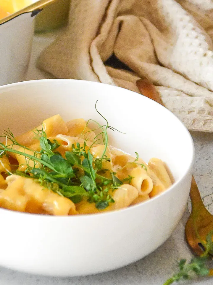 Vegane Mac and Cheese mit cremiger Sauce und frischen Kräutern in einer weißen Schüssel