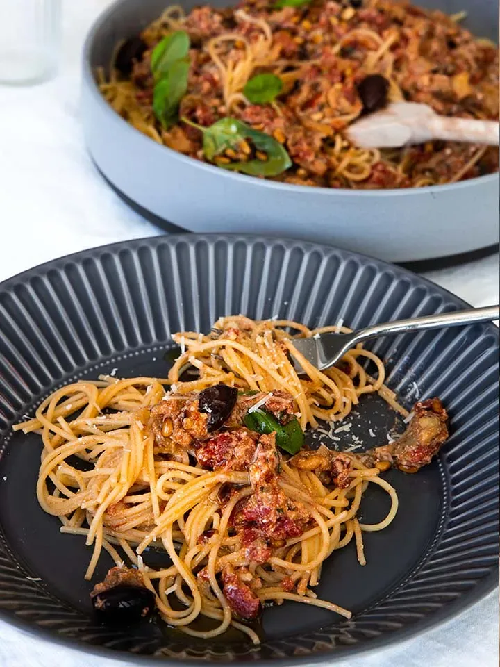 Vegane Spaghetti alla Norma mit Tomatensauce, Oliven und Basilikum auf einem Teller