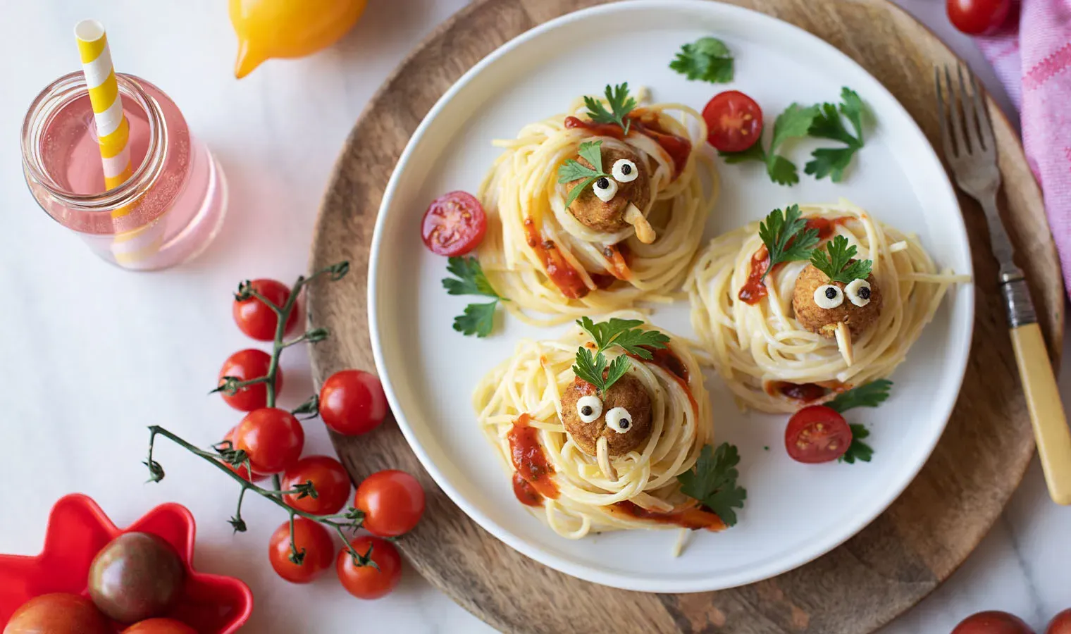 Vögelchen in Spaghettinestern: Gemüsebällchen als kleine Gesichter mit Augen und Blättern auf einem Teller