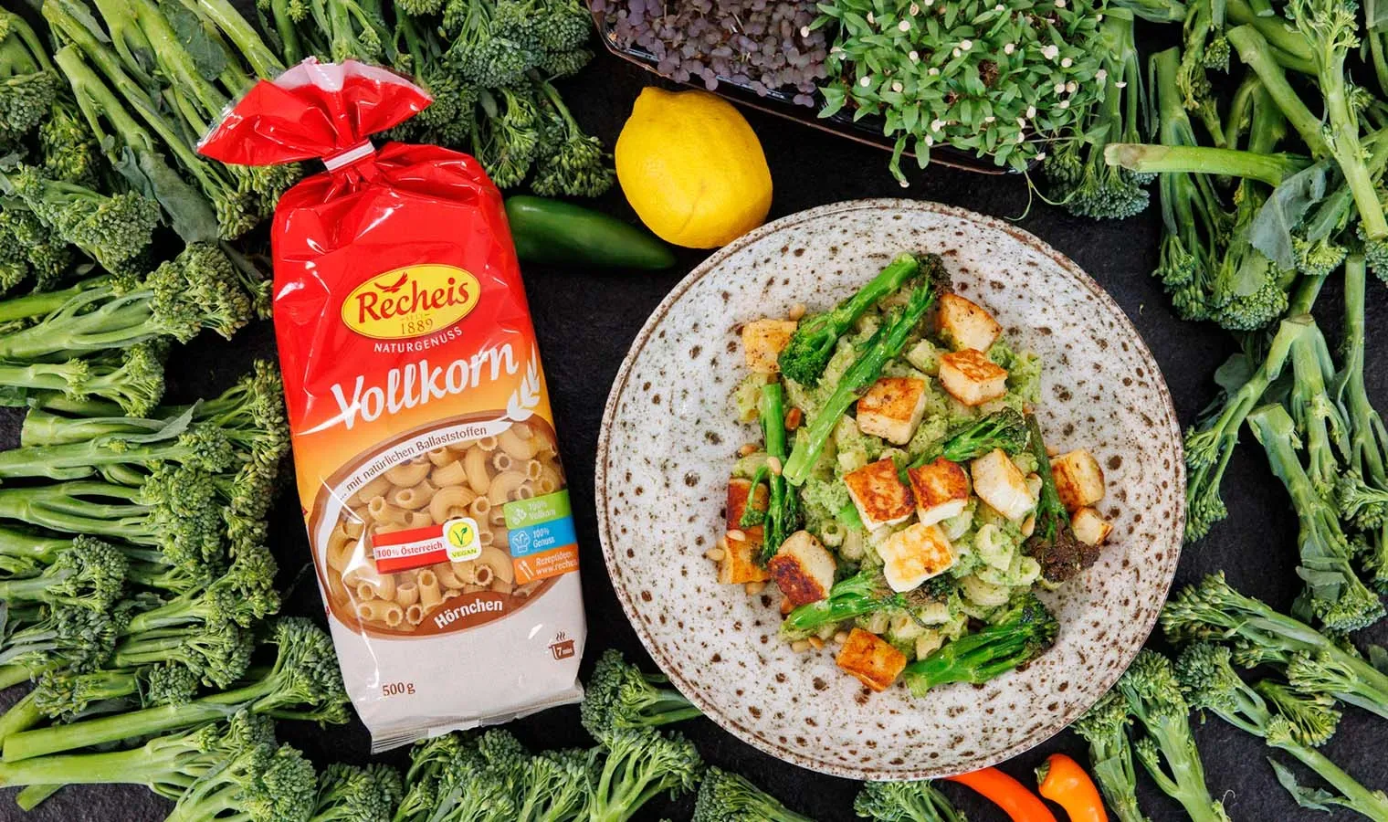 Vollkorn-Hörnchen mit Stangenbrokkoli-Pesto und Halloumi auf einem Teller, umgeben von Brokkoli und Zitrone