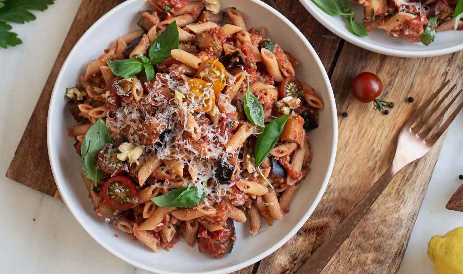 Vollkorn-Mini-Penne mit veganem Ragù in Tomatensauce, mit Basilikum und geriebenem Käse auf einem Teller