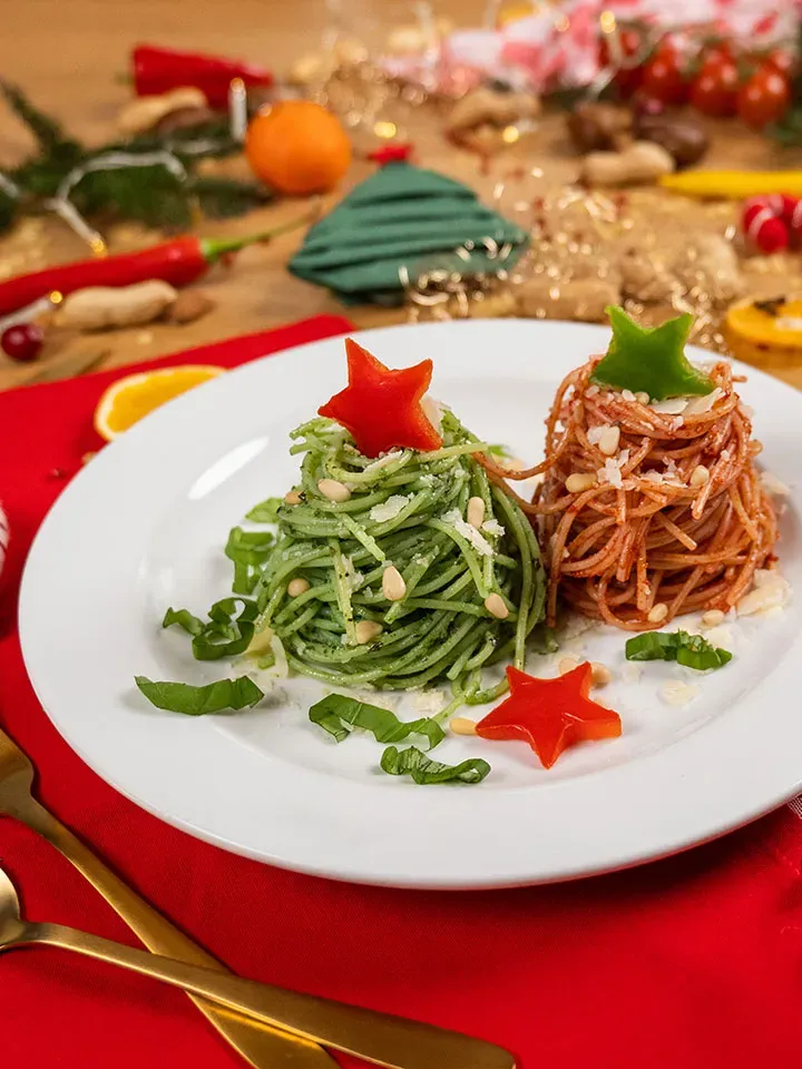Weihnachtlich angerichtete grüne und rote Spaghetti mit Paprikasternen auf einem weißen Teller