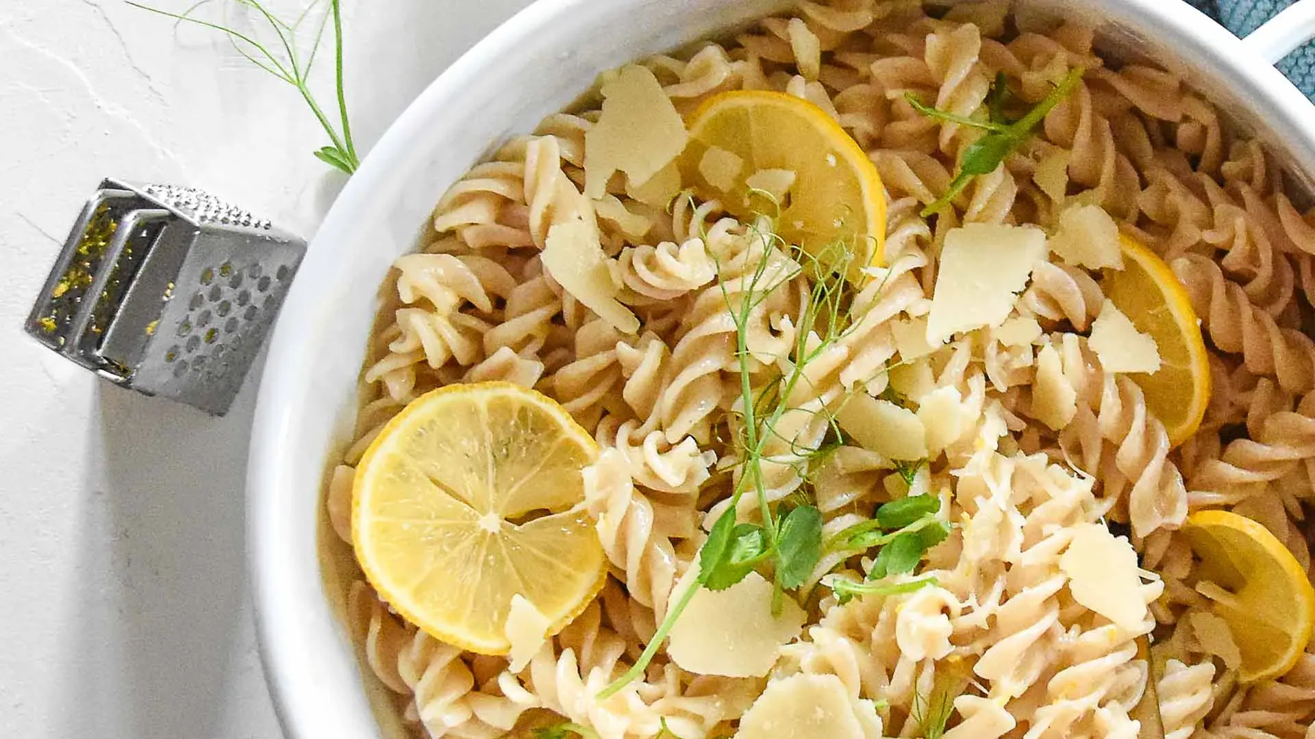 Nudeln mit Zitronensauce, Zitronenscheiben, Parmesan und Kräutern in einer weißen Schüssel