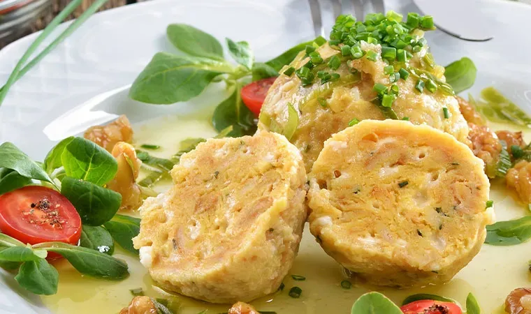 Zwiebelknödel auf einem Teller mit Salat, Tomaten und Walnüssen